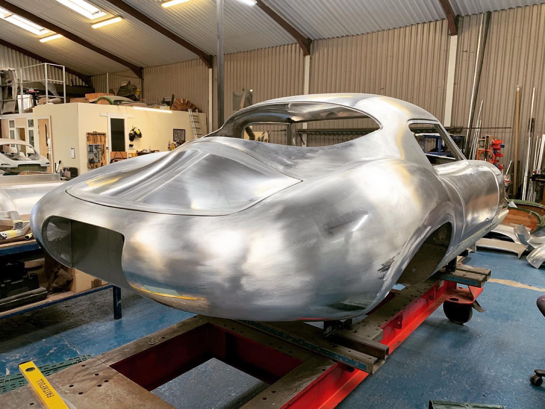 Completed hand-formed aluminium coachbuilt body shell on the workshop rig
