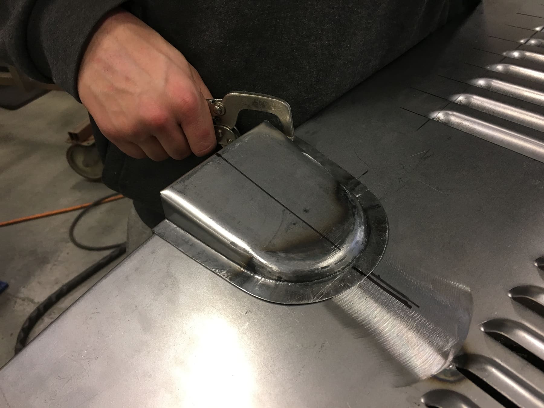 Hand-clamping a curved metal panel during shaping